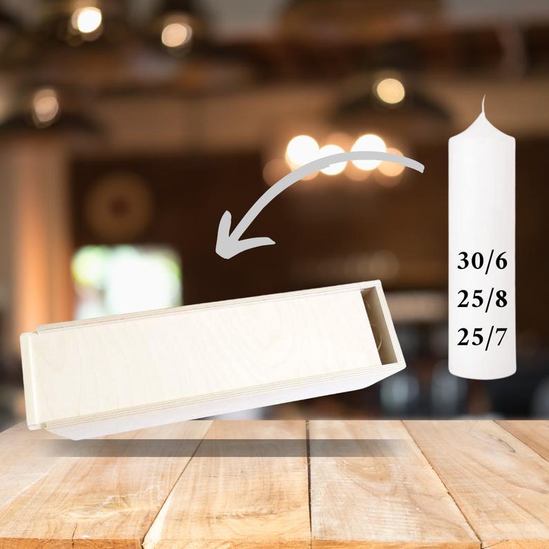 May include: A white wooden box with a white pillar candle. The candle is labeled with the numbers 30/6, 25/8, and 25/7. The box is tilted to the side, and the candle is standing upright.
