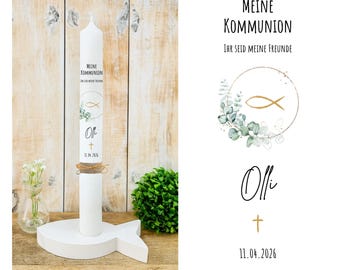 Può includere: Una candela bianca da comunione con il testo "MEINE KOMMUNION" e "IHR SEID MEINE FREUNDE". La candela ha un simbolo di pesce dorato e il nome "Olli" con una croce e la data "11.04.2026". Si trova su un supporto a forma di pesce bianco.