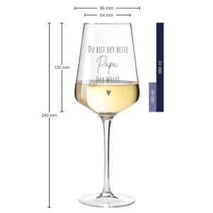 May include: A clear glass wine glass with a 560 ml capacity. The glass has a wide bowl and a long stem. It is engraved with the text "Du bist der beste Papa der Welt!" which translates to "You are the best Dad in the world!" in English. The glass is filled with white wine.