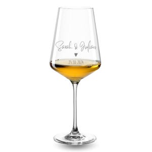 May include: A clear glass wine glass filled with a golden liquid. The glass features the printed text Sarah & Julian, a small heart icon, and the date 25.10.2024 in a dark grey font. The stem is slender and connects to a circular base.