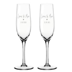 K&ouml;nnte beinhalten: Zwei klare Champagnerfl&ouml;ten aus Glas mit dem Text "Leon & Mia" und dem Datum "25.09.2025" auf jeder.