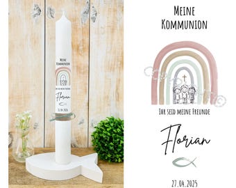 Può includere: Una candela bianca con la scritta "Meine Kommunion" e un disegno arcobaleno, posta su un supporto bianco a forma di pesce. La candela include il nome "Florian" e la data 27.04.2025. Un piccolo vaso con fiori bianchi a sinistra.