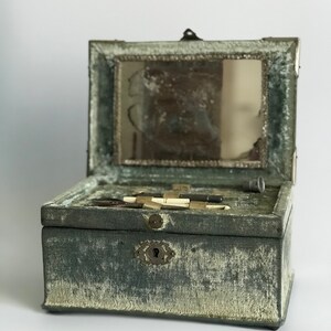 May include: A vintage green velvet jewelry box with a hinged lid and a small mirror inside. The box has a metal latch and a keyhole.