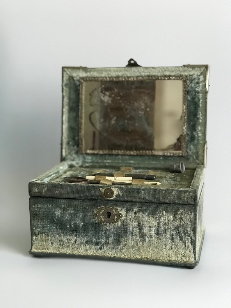 May include: A vintage green velvet jewelry box with a hinged lid and a small mirror inside. The box has a metal latch and a keyhole.
