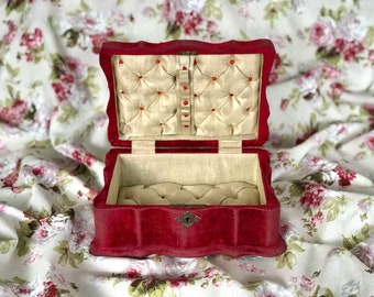 May include: A red velvet jewelry box with a scalloped edge and a satin lining. The box has a small keyhole and a decorative metal clasp.