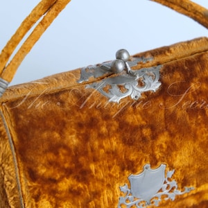 May include: A vintage velvet handbag with a silver clasp and ornate metal accents. The bag is a rich mustard yellow color.