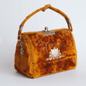 May include: A vintage velvet handbag with a silver clasp and ornate metal accents. The bag is a rich orange color and has a top handle.