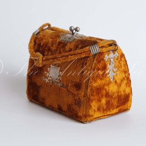 May include: A small, vintage, mustard yellow velvet handbag with silver metal accents and a clasp.