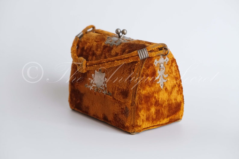 May include: A small, vintage, mustard yellow velvet handbag with silver metal accents and a clasp.