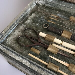 May include: A vintage sewing kit with a variety of tools, including scissors, needles, and thimbles. The tools are arranged in a velvet-lined box.