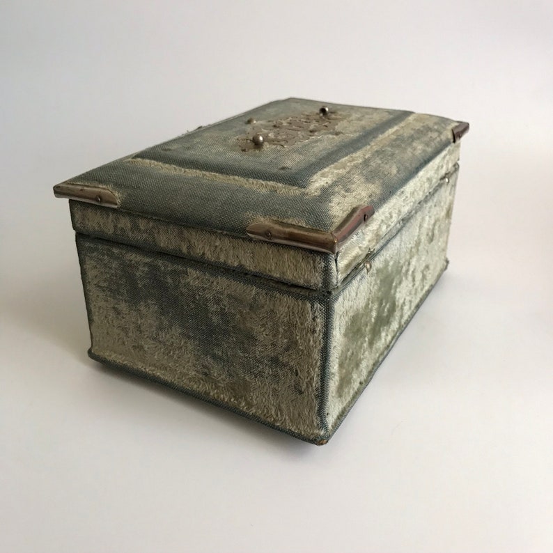 May include: A vintage, rectangular, green velvet jewelry box with silver metal accents and a floral design on the lid.