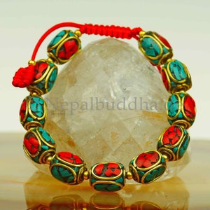 May include: A red and turquoise bracelet with gold accents. The bracelet is made of small, round beads and is tied with a red cord.