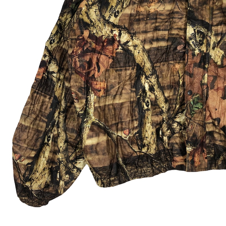 May include: A brown, green, and tan camouflage jacket with a button-up front. The jacket has a relaxed fit and a slightly cropped length.