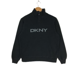 May include: Black long-sleeved sweatshirt with a half-zip fastening and the DKNY logo in a silver-grey colour.