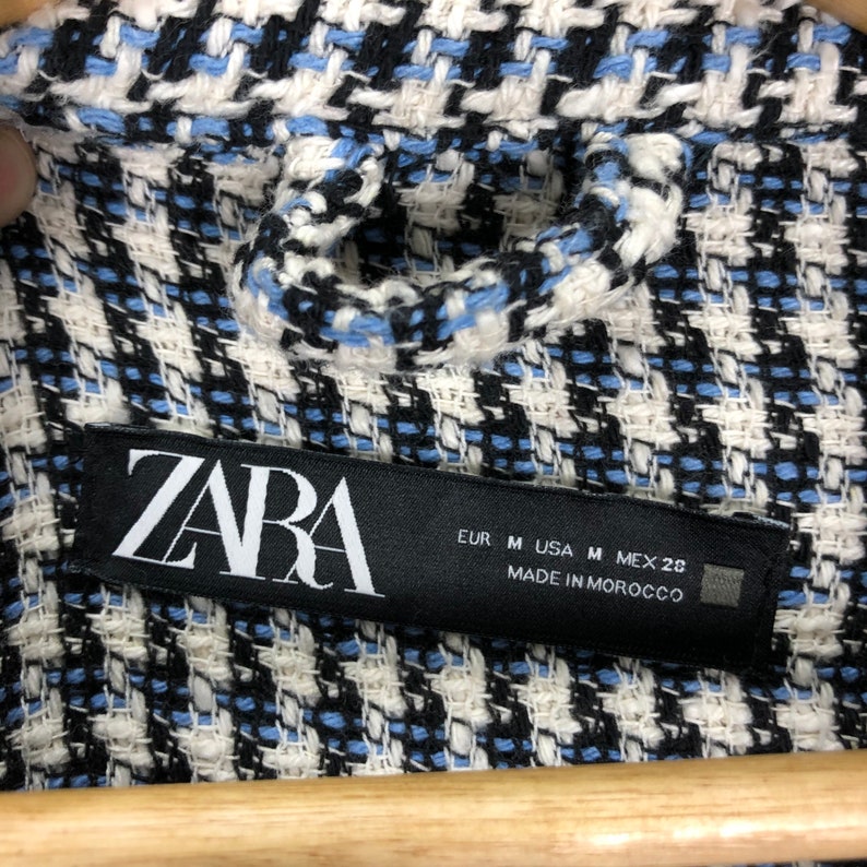 May include: A black and white label with the word "ZARA" in white lettering. The label also includes size information: EUR M, USA M, MEX 28. The label states "MADE IN MOROCCO".