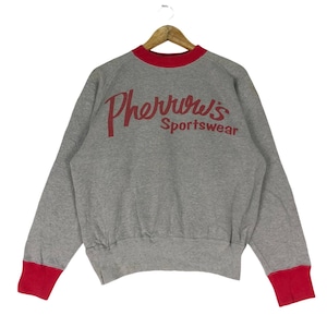 May include: A grey sweatshirt with red trim around the neck and cuffs. The sweatshirt has a red logo that says "Pherrwvs Sportswear" on the back.