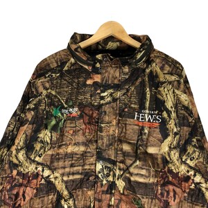 May include: Camouflage jacket with a green frog logo and the text "Goverair Hewes" in white.