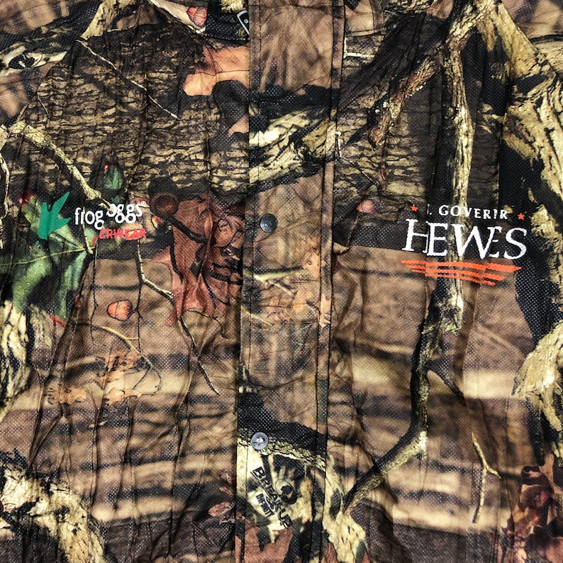May include: A brown, green, and black camouflage print button-up shirt with the text "Frog 365" and "L. Goverir Hewes" printed on the front.