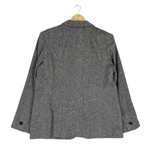 May include: A gray tweed blazer with a single button closure and long sleeves. The blazer has a classic fit and is made of a soft, comfortable fabric.