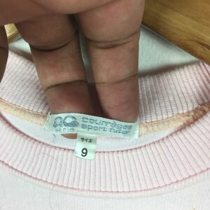 May include: Pink sweatshirt with a white tag that says "Courreges Sport Futur Paris" and a size tag that says "Size 9".