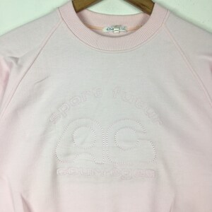 May include: A pink sweatshirt with a white embroidered logo that says "Sporty Fashion" and "AC" in a stylized font.