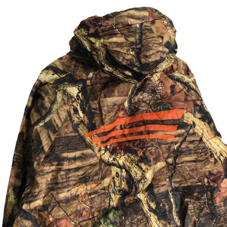 May include: Camouflage jacket with a hood and orange stripes. The jacket is made of a lightweight material and has a relaxed fit.