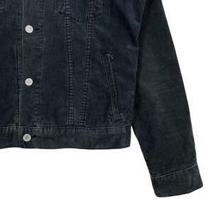 May include: A dark gray corduroy jacket with a button closure and two pockets. The jacket has a classic denim style.