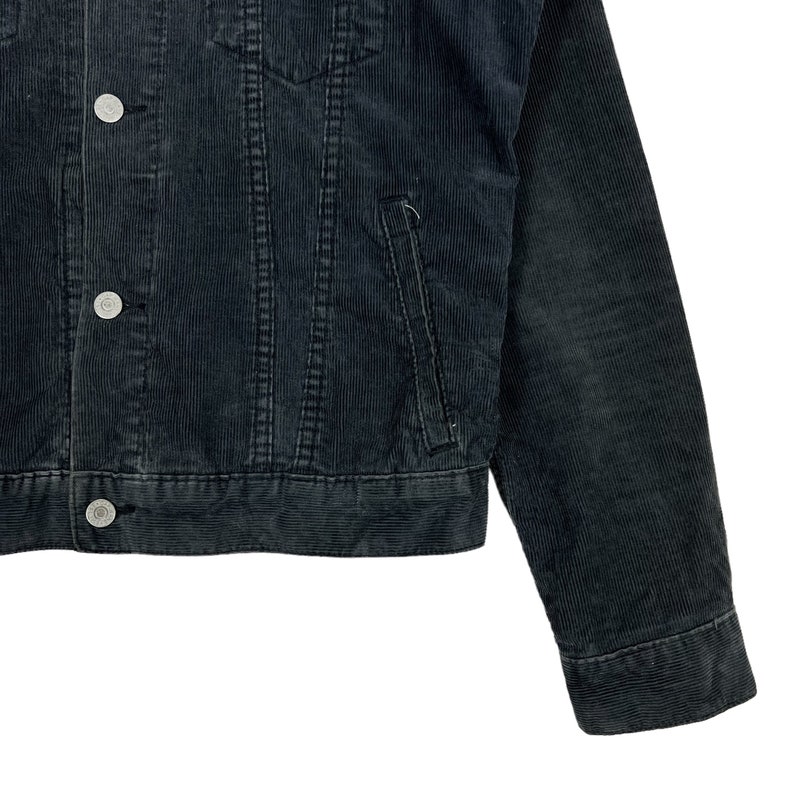 May include: A dark gray corduroy jacket with a button closure and two pockets. The jacket has a classic denim style.