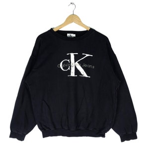 Puede incluir: Sudadera negra con un logotipo blanco de Calvin Klein Jeans con una "K" grande en una fuente desgastada.