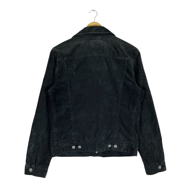 May include: A black corduroy jacket with a button-up front and long sleeves. The jacket has a classic denim jacket style.