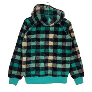 Op de afbeelding: Een groene en zwarte geruite fleece hoodie met een capuchon met trekkoord. De hoodie heeft een turquoise voering en een klein geborduurd ontwerp op de capuchon.