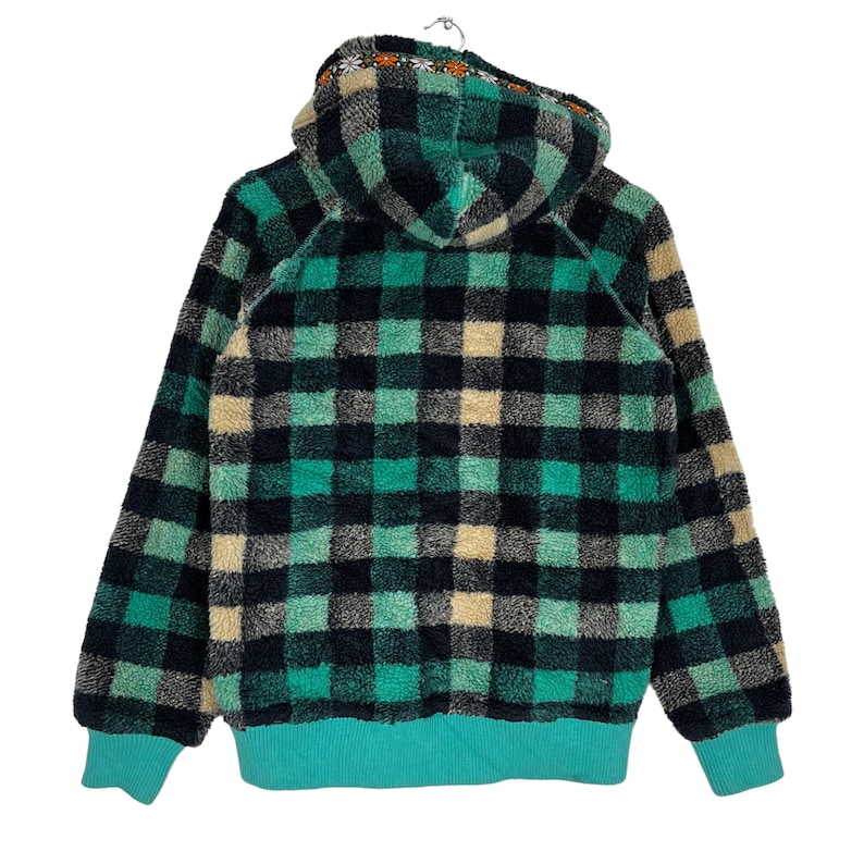 Op de afbeelding: Een groene en zwarte geruite fleece hoodie met een capuchon met trekkoord. De hoodie heeft een turquoise voering en een klein geborduurd ontwerp op de capuchon.
