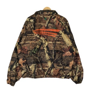 May include: A brown and green camouflage jacket with an orange stripe across the back. The jacket has a zipper closure and a stand-up collar.