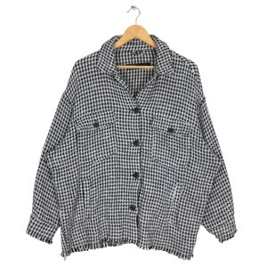 May include: A black and white checkered button-up shirt with frayed edges. The shirt has two flap pockets on the front and a button closure.