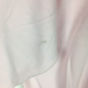 May include: Close-up of a white fabric with a small, light brown stain.