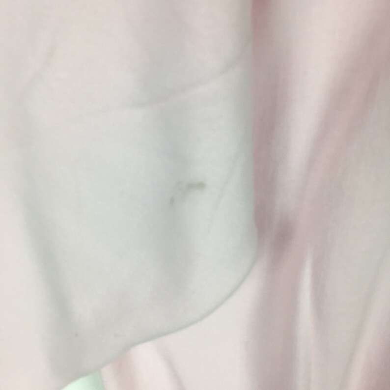 May include: Close-up of a white fabric with a small, light brown stain.