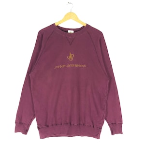 May include: A maroon sweatshirt with a gold embroidered logo that says "John Player Special" and a smaller gold embroidered logo of the letters "JP" above the text.
