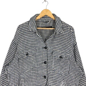 May include: A white and blue checkered button-up shirt with long sleeves and two flap pockets. The shirt has a collared neckline and a button closure.