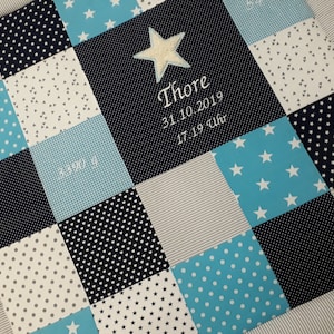 Könnte beinhalten: Eine blaue und weiße Patchwork-Babydecke mit einem Stern und dem Namen "Thore" in der Mitte gestickt. Das Datum "31.10.2019 17.19 Uhr" ist ebenfalls auf die Decke gestickt.