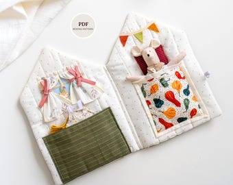 Könnte beinhalten: Ein handgefertigtes Stoff-Spielbuch in Hausform mit einer Spielzeugmaus. Das Buch hat eine grüne Tasche, ein Fenster mit Vorhängen und ein Bett mit einer bunten gemusterten Decke. Der Text "PDF Sewing Pattern" ist sichtbar.