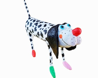 Può includere: Una stravagante statuetta di cane dalmata. Il cane ha un corpo bianco con macchie nere, un naso rosso e accenti colorati sui piedi. Le orecchie e la coda del cane sono a strisce bianche e nere. La statuetta ha un design giocoso e fumettistico.