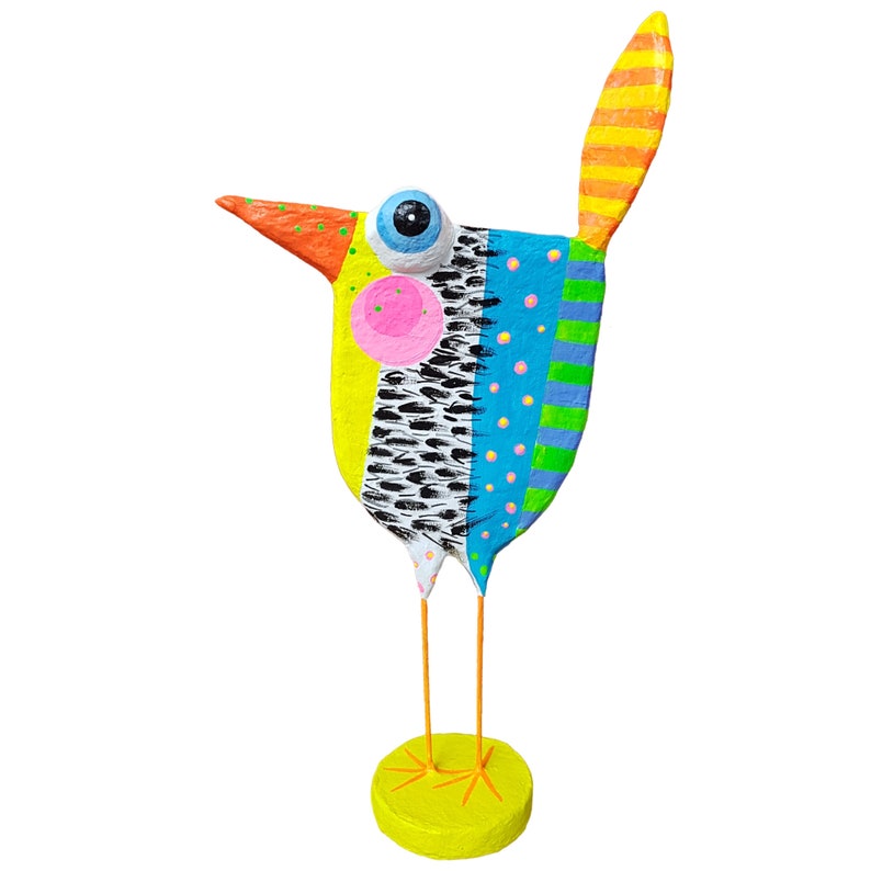 Detailaufnahme einer handgefertigten Vogel-Skulptur aus Pappmaché im modernen naiven Kunststil. Zeigt die vertikal segmentierten Muster: links Zitronengelb mit rosa Wange, Mitte schwarz-weißes Federmuster, rechts Hellblau mit bunten Punkten und grün-blauen Querstreifen. Teil des orangefarbenen gepunkteten Schnabels und des gestreiften orange-gelben Schwanzes. Ein einzigartiges, farbenfrohes Kunst-Unikat für Deko-Zwecke.