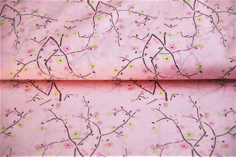May include: Pink fabric with a repeating pattern of black branches and pink and yellow flowers.