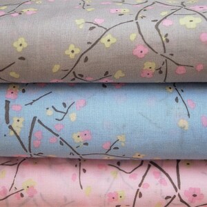 May include: Three fabric swatches with a floral pattern. The top swatch is gray with pink and yellow flowers. The middle swatch is light blue with pink and yellow flowers. The bottom swatch is pink with pink and yellow flowers.