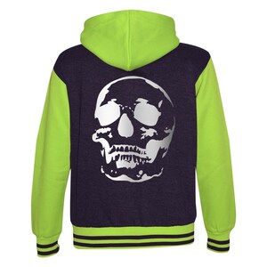 Könnte beinhalten: Eine grüne und violette Kapuzenjacke mit einem weißen Totenkopf-Motiv auf der Rückseite. Die Jacke hat einen gerippten Strickkragen, Bündchen und Bund.