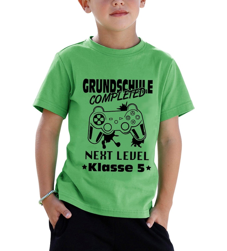 Das Bild zeigt ein Bügelbild, das für Kinder gedacht ist, die die Grundschule abgeschlossen haben. Es zeigt einen schwarzen Spielcontroller als Hauptmotiv, umgeben von dem Text „GRUNDSCHULE COMPLETED“ und „NEXT LEVEL Klasse 5“. Das Design kombiniert spielerische Elemente aus der Gaming-Welt mit einem feierlichen Anlass, wodurch es ideal für Shirts oder andere personalisierte Artikel ist, die den Übergang zu einer neuen Schulstufe markieren. Ein kreatives Detail für stolze Schüler!