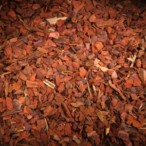 May include: A close-up of a pile of red cedar mulch. The mulch is made up of small, shredded pieces of wood.