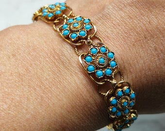Puede incluir: Pulsera dorada con diseños florales en turquesa. La pulsera está compuesta por múltiples eslabones en forma de flor conectados por delicadas cadenas doradas. Las piedras turquesas están engastadas en el centro de cada flor.