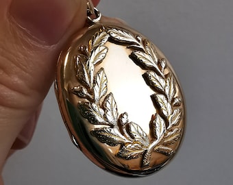 May include: Gold oval locket with a detailed leaf design around the edge.