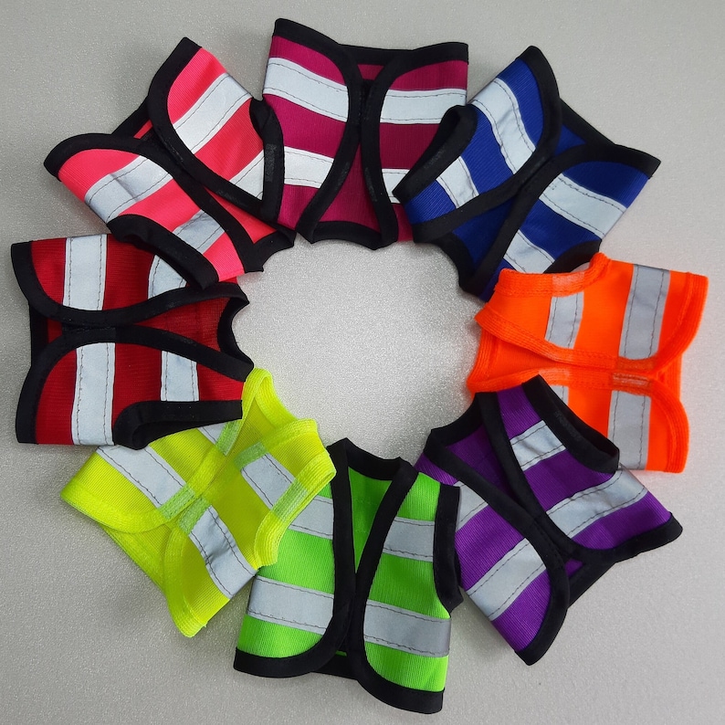 Puede incluir: Diez chalecos de seguridad coloridos en diferentes colores, incluyendo rojo, naranja, amarillo, verde, azul y morado. Los chalecos est&aacute;n hechos de un material reflectante y tienen un ribete negro.